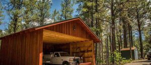 A parked truck in front of a wooden shed.